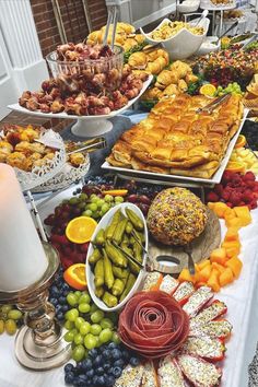 a table filled with lots of different types of food on top of a white table cloth