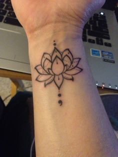 a woman's wrist with a lotus tattoo on it