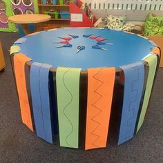 a table made out of cardboard with scissors on it in a room filled with children's furniture