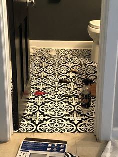 a black and white tiled floor in a bathroom with an open door to the toilet