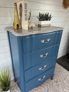 a blue dresser with gold handles and drawers on top of it in a living room