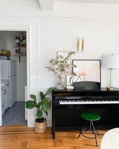 there is a black piano in the living room with a green stool next to it