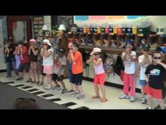 a group of young children standing in front of a store counter with their hands up