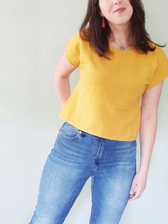 a woman standing in front of a white wall with her hands on her hips and looking at the camera