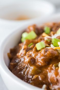 a white bowl filled with chili and green onions