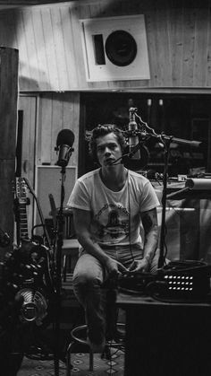 black and white photograph of a man sitting in front of a recording equipment set up