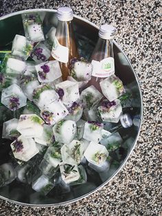 there are ice cubes with flowers in them and two bottles on the table next to it