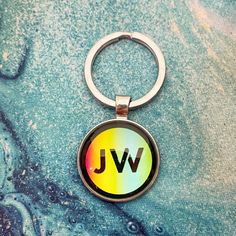 a keychain with the word jw on it is sitting next to a pair of jeans