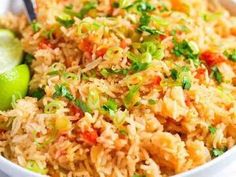 a bowl filled with rice and vegetables next to a lime wedged in the side