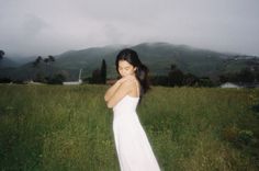 a woman in a white dress standing in a field