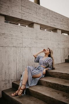 a woman sitting on some steps with her hand in her mouth and looking up at the sky