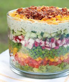 a layered salad in a glass dish on top of a table