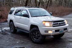 a white suv parked in the middle of a forest