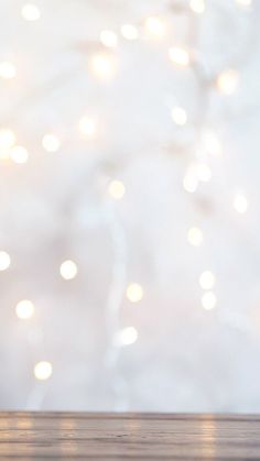 an apple sitting on top of a wooden table next to a white wall with lights