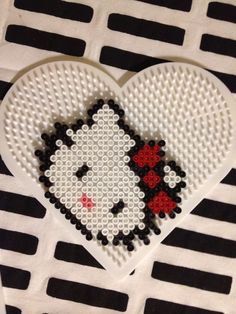 a white heart with a black and red hello kitty on it's side sitting on top of a table