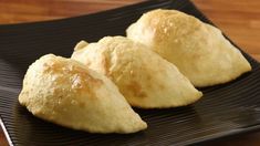 three small pastries on a black plate