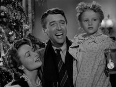 a man and two women standing in front of a christmas tree