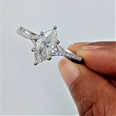 a person holding an engagement ring with a diamond in it's center and two diamonds on the band