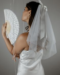 a woman in a wedding dress holding a white fan