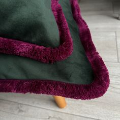 a green and purple couch with a wooden leg on the floor in front of it