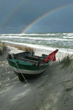 a boat on the beach with a rainbow in the background