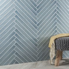 a wooden bench sitting in front of a blue wall with white chevron tiles on it