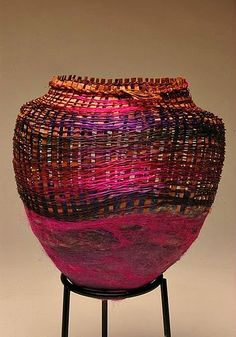 a large woven vase sitting on top of a table next to a white wall and floor