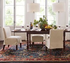 a dining room table with chairs and a rug on the floor in front of it