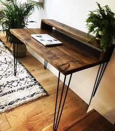 a wooden table with hairpin legs and plants on top