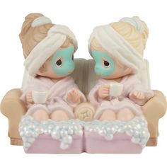 two figurines are sitting on a couch holding cups and looking at each other