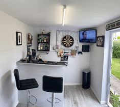 a bar with two chairs and a television on the wall behind it in a room