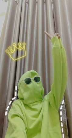 a person in a frog costume is pointing to the sky with his hand and wearing sunglasses