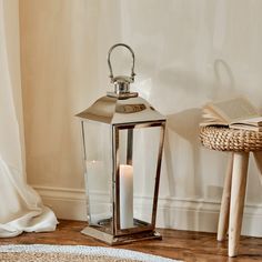 a candle is lit next to an open book on the floor in front of a white curtain