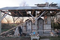 a man standing in front of an old building with wood on the floor and roof