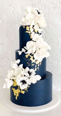 a three tiered blue cake with white flowers on top