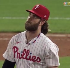 a man with a beard wearing a phillies baseball uniform on the pitchers mound at a baseball game