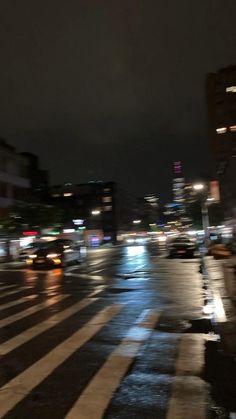 a city street at night with cars driving on it