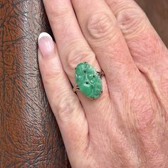 Embodying the spirit of the Art Deco era, this lovely jade ring captures simplicity and beauty in perfect harmony. Crafted in the 1930s, the ring features a graceful split shank mounting in 9 karat white gold, designed to showcase the stunningly carved piece of bright green jade. Its smooth contours and vibrant hue draw the eye, celebrating the natural elegance of the stone.  This beautifully carved, vibrant slice of natural jade measures 18.5 mm north to south and 11 mm across, with a thickness of 2 mm, creating a striking focal point. This ring is a size 6.25 and is marked with '9c' for its 9 karat gold content, weighing a delicate 2.67 grams.  More than just an adornment, this piece invites you to embrace the sophistication of a bygone era, offering a touch of timeless elegance that enh Carved Jade, Ring White Gold, Bygone Era, Jade Ring, Perfect Harmony, Jade Carving, Split Shank, Art Deco Era, Natural Jade