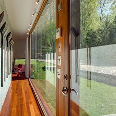 an open door leading to a room with wood flooring and glass walls on both sides