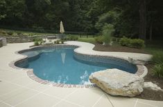 an empty swimming pool surrounded by trees and rocks in the middle of a garden area