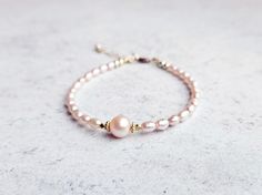 This gorgeous bracelet is made from natural rice shaped pink freshwater pearls with a round AAA grade pink pearl at the center framed by vermeil beads.  The pearls are dainty and distinctively pink, perfect for stacking with any bracelets from my shop! All finishings are gold filled, making the bracelet tarnish resistant and suitable for everyday wear. The length is 6.5 inches with 1 inch extension chain. Please message me if you need a customized size or without extension chain, I need to confi Pink Pearl Bracelet Gift, Delicate Handmade Pink Pearl Bracelet, Pink Pearl Drop Bracelet As Gift, Adjustable Pink Pearl Bracelet With Pearl Drop, Delicate Pink Pearl Bracelet As A Gift, Delicate Pink Pearl Bracelet As Gift, Delicate Pink Pearl Bracelet For Gift, Pink Pearl Drop Bracelet For Wedding, Delicate Pink Pearl Bracelet Gift