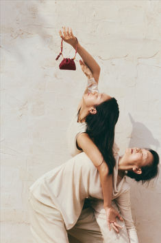 two women standing next to each other with one holding an object in the air