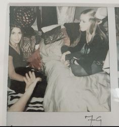 an old photo of two women sitting on a bed with their hands in the air