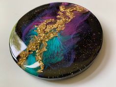 a black and purple plate with gold leaf designs on the top, sitting on a white surface