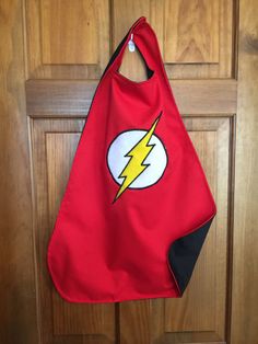 a red bib hanging on a wooden door with a flash symbol in the center