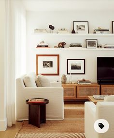 a living room filled with furniture and a flat screen tv sitting on top of a wooden shelf