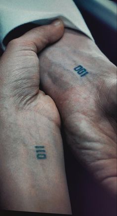 two hands holding each other with tattoos on them