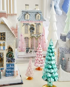 several small christmas trees are sitting on a table next to miniature houses and snowflakes