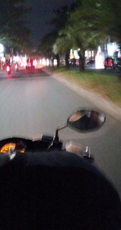 the view from inside a motorcycle driving down a street at night