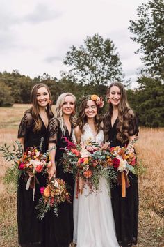 the bridesmaids are wearing black dresses and holding bouquets in their hands while posing for a photo